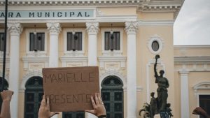 Crowd holding a sign 'MARIELLE PRESENTE' at Rio's city hall.